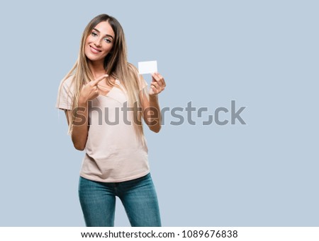 Young pretty woman smiling confident, offering a business card, has a thriving business, copy space to write whatever you want