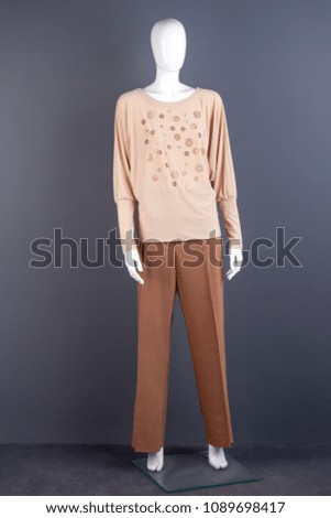 Full length mannequin in women apparel. Mannequin clothed in women blouse and formal trousers on grey background.