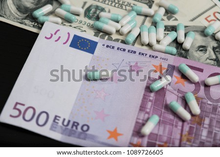 A bunch of pills and tablets on euro and dollar banknotes for background.
