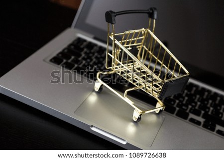 Online shopping. A laptop and mini shopping cart and gadgets