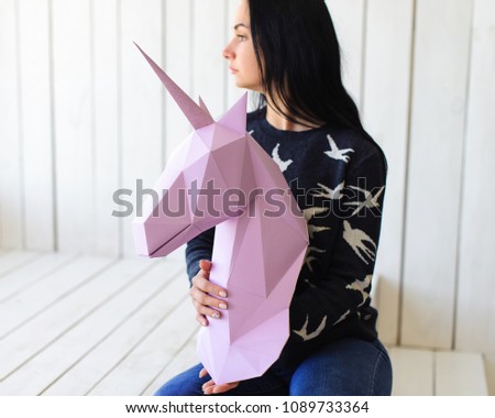 The girl holds a pink unicorn 3d Unicorn model. Artwork.