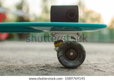 Side view of the blue plastic penny skateboard with action camera on it. Front view. The concept of city travelling, vlogging, modern lifestyle