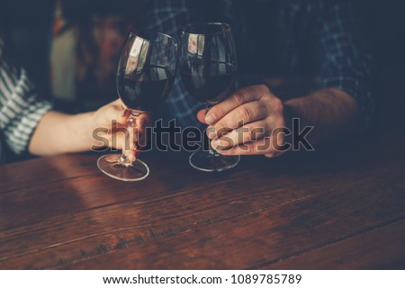 Man and female toasting with glasses of red wine in the restoran. Wine in a glass, selective focus, motion blur. Red wine in a glass. Sommelier pouring the wine into the glass. Thanksgiving Day.