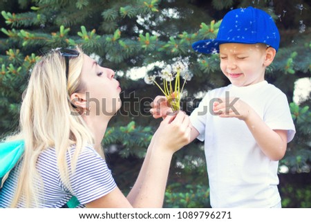 Mother and little son blowing on a dandelion.