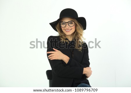 beautiful young girl with glasses and hat, wearing a black jacket on a white background