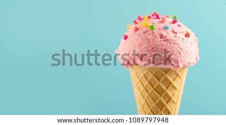 Ice cream cone close-up. Pink Icecream scoop in waffle cone over blue background. Strawberry or raspberry flavor Sweet dessert decorated with colorful sprinkles, closeup Royalty-Free Stock Photo #1089797948