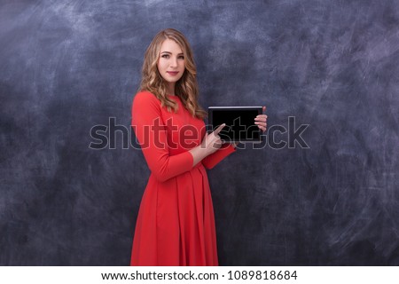 A young beautiful girl holds a black tablet in her hands. Various human emotions, body language.Girl holding a tablet