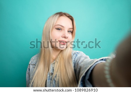 Romantic long-haired woman taking selfie looking at phone camera enjoying her beauty and youth.