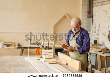 portrait of old repairman working with wooden board. woodworking concept.