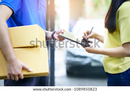 Delivery concept. Delivery man delivers package at home and woman receiving by signing electronic  or gadget acceptance at doorway. Logistic for online shopping order sending by postman or messenger


