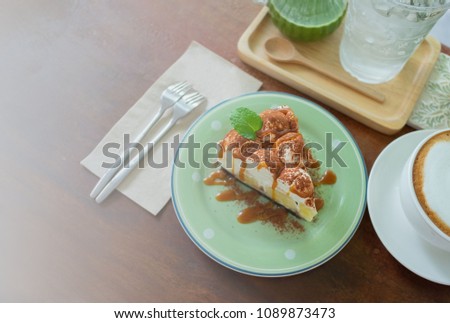 Flat lay picture of a slice of cake on a green plate, a cup of cappuccino and a glass of matcha green tea on wooden table. Image with selective focus and copy space.