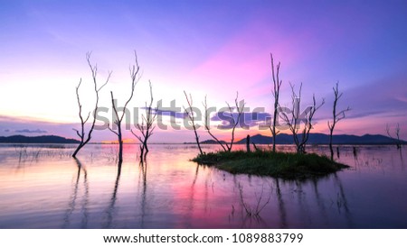 beautiful sunset on the reservoir , reflection of silhouettes dry tree , landscape thailand