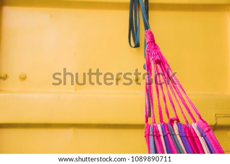 Colorful canvas hammock with rope hanging on the shipping metal container in the resort.