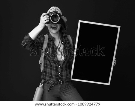 Searching for inspiring places. young tourist woman with backpack and blackboard taking photo with DSLR camera isolated on background