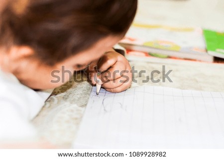 A baby girl is writing on the paper