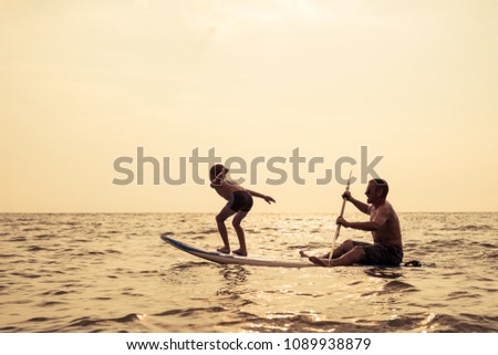 Father and baby son playing on the beach at the day time. People having fun outdoors. Concept of summer vacation and friendly family.