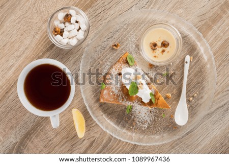 Tasty cake with mint leaves and ice cream balls, white tea cup on a wooden table. Sweet dessert background. Top view.