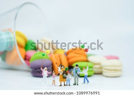 Miniature People  : Big Family with balloon standing in front of glass full with colorful macaroon use as world of happiness , take care of children and beautiful life .
