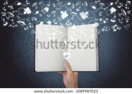 Hand holding book with creative business sketch. Education and innovation concept 