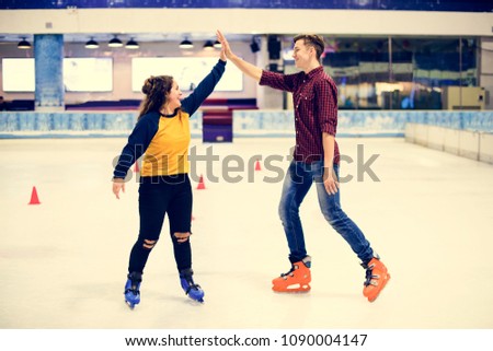 Friends giving each other a high five a they are ice skating on the ice rink