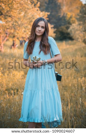 Portrait of a beautiful girl in the garden. Girl in a blue dress with a sprig of white flowers in her hands. 