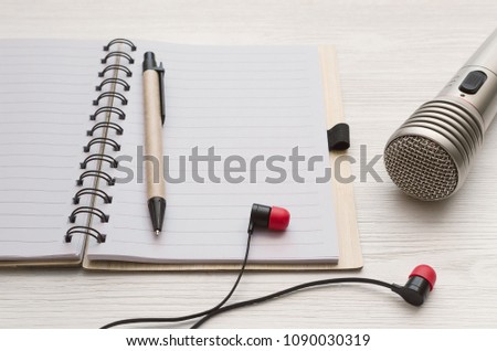 Audio recording studio desk table. Karaoke mock up. Microphone, headphones and blank page notepad with copy space for song lyrics on white table background.