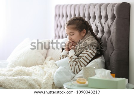Sick little girl with cough suffering from cold in bed Royalty-Free Stock Photo #1090043219
