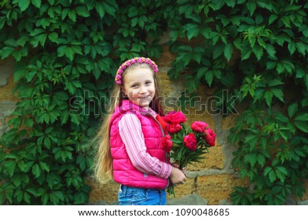 Portrait of a lovely little girl with a bouquet of peonies