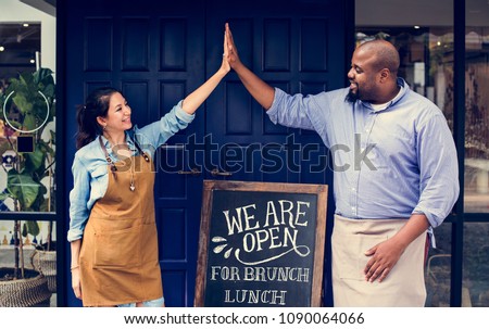 Cheerful business owners standing with open blackboard Royalty-Free Stock Photo #1090064066
