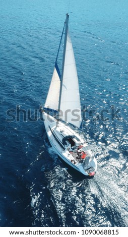 Aerial photo of luxury yacht - sail boat cruising in deep blue waters of Sanorini island, Cyclades, Aegean, Greece