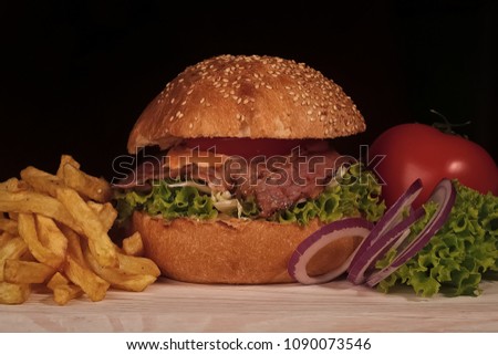 One big tasty appetizing fresh burger of green lettuce red tomato cheese bacon slice meat cutlet violet oinion and white bread bun with sesame seeds on black backgeound closeup, horizontal picture