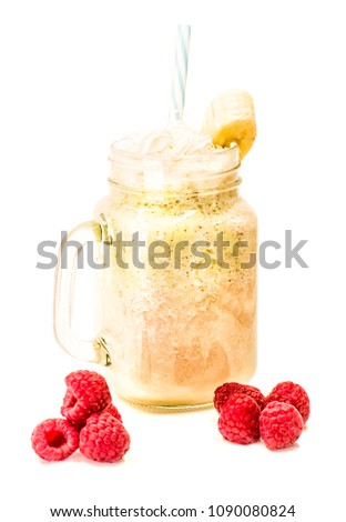banana and kiwi milkshake in mason jar with creme on top and drinking straw decorated with raspberries isolated on white background