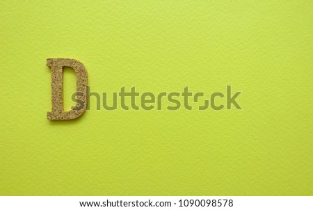 “D” alphabet on yellow background. Wooden alphabet.