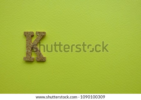 “K” alphabet on yellow background. Wooden alphabet.