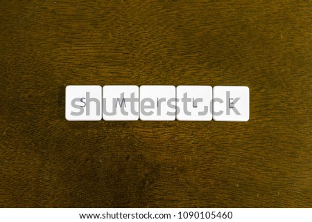 SMILE word written on plastic keyboard alphabet with dark background