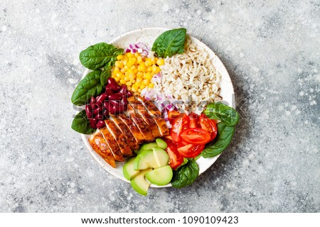 Homemade Mexican chicken burrito bowl with rice, beans, corn, tomato, avocado, spinach. Taco salad lunch bowl Royalty-Free Stock Photo #1090109423