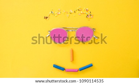 Glasses and Colored Rainbow Sprinkles with marsh mallow shape smile face on yellow background.Happy smile concept