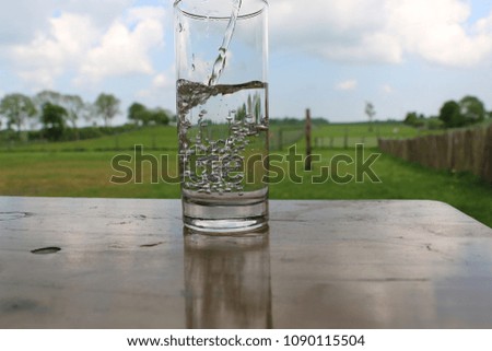 fresh water is falling in a glass on the table in the garden