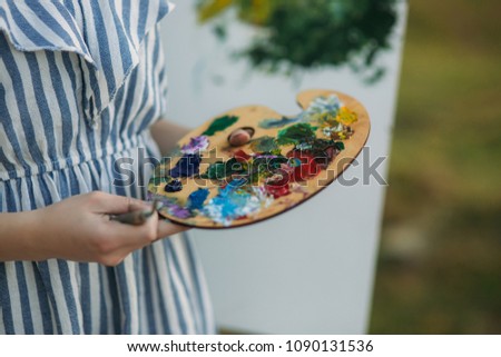 Girl is holding Palette with paints and spatula