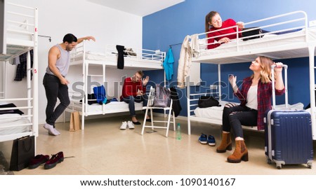 Young cheerful  smiling men and women friendly interacting while staying in modern comfy hostel Royalty-Free Stock Photo #1090140167