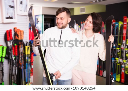 Portrait of ordinary man and woman buying skis in store
