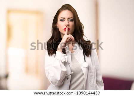 Doctor woman making silence gesture on unfocused background