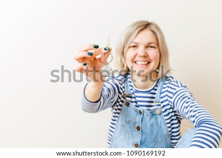 Photo of woman with keys from apartment against blank wall
