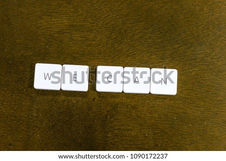 WE CAN word written on plastic keyboard alphabet with dark background