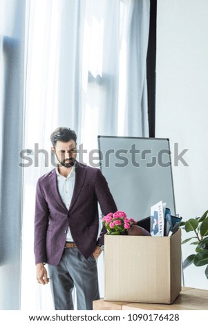 handsome young businessman looking at box of personal stuff in office