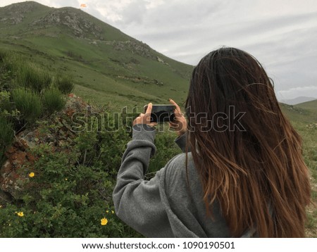 Young beautiful woman taking a smartphone shot of mountains