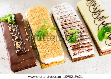 Beautiful Delicious dessert cheesecakes and chocolate cake  decorated with  mint leaves  on a white trendy background. Group of four different types of sweets.