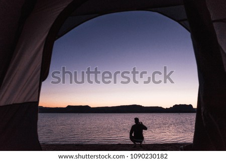 Man sitting on shore at sunset, taking picture of the lake, Grand Canyon, USA