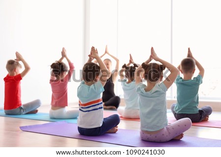 Little children and their teacher practicing yoga in gym Royalty-Free Stock Photo #1090241030