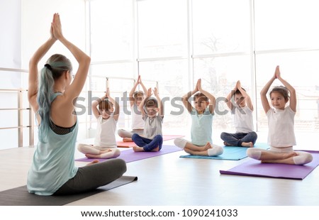 Little children and their teacher practicing yoga in gym Royalty-Free Stock Photo #1090241033